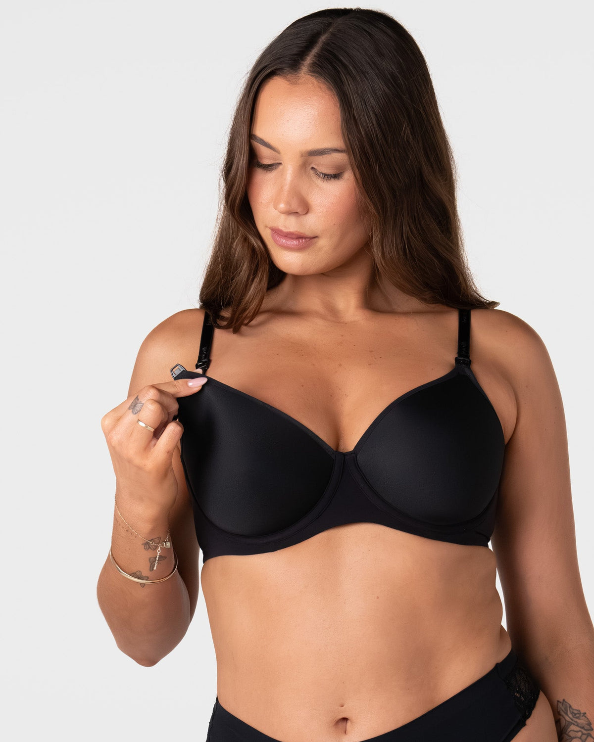 Model unclipping the traditional nursing clip on the Forever New black breastfeeding bra with drop-down cup for easy feeding access